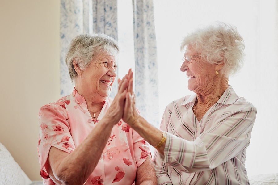 Två äldre kvinnor slår samman sina händer.