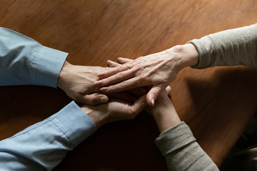 Två äldre personer håller varandras händer.