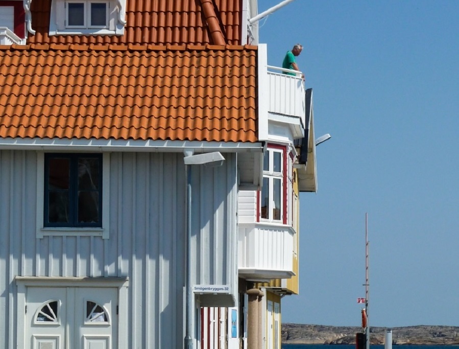 Balkong och burspråk på ljusblått hus med rött tak
