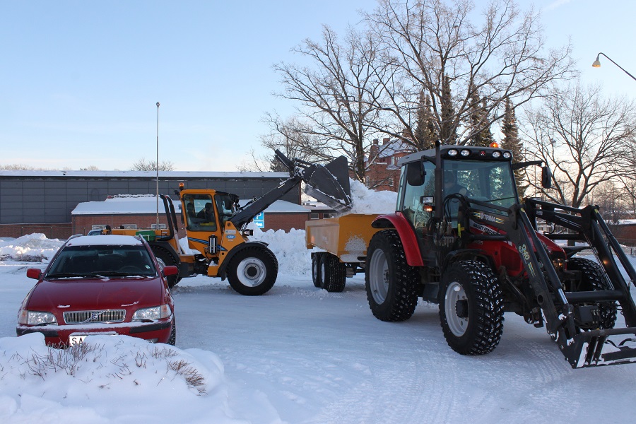 Lastmaskin lastar snö i en traktorkärra