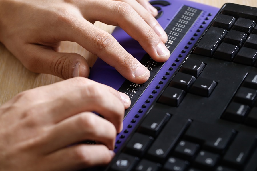 Blind person använder tangentbord för braille-skrift.