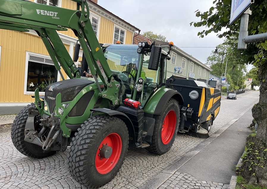Traktor kör sopmaskin på gata i Askersund.